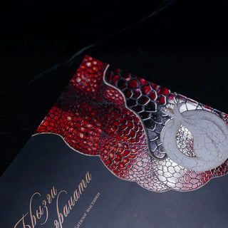 Detailed view of Raised Spot UV Varnish on a pomegranate illustration, showing the glossy, 3D textured seeds and silver metallic accents on a dark book cover.