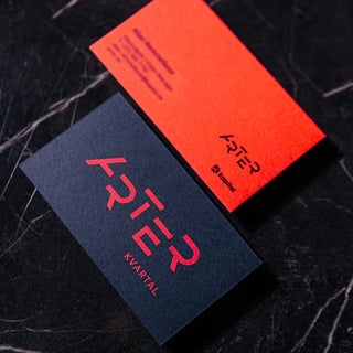 Black and orange business cards for Arter Kvartal with a red gradient "ARTER" logo on the black card and a black logo on the orange card, styled on a dark marble background