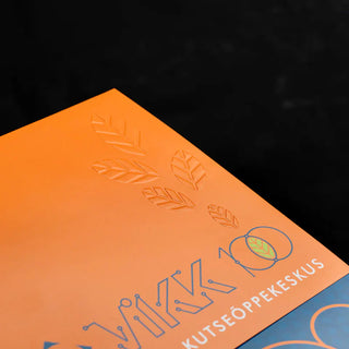 Close-up of debossed printing on an orange brochure featuring leaf patterns