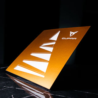 Kuldsel metalliktaustal valge logo ja graafiline element. Minimalistlik luksuslik trükis geomeetriliste kujundite ja sportliku disainiga. | Trükikoda Brandcafe