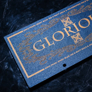 Intricate glitter screen print on blue pearlescent cardstock featuring gold screen print text and ornate filigree patterns.