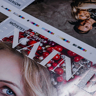 Silver glitter screen printing on white magazine cover featuring a portrait and red decorative ornaments.