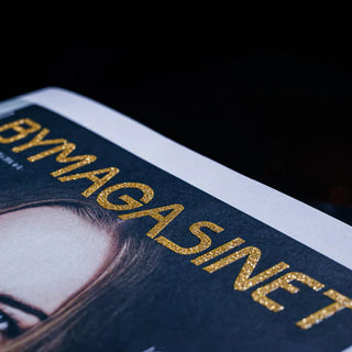 Logo featuring a textured gold glitter screen print on a dark magazine cover.