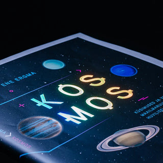 Holographic foil book cover for "Kosmos" by Ene Ergma, featuring iridescent shimmering typography and space-themed illustrations of planets.
