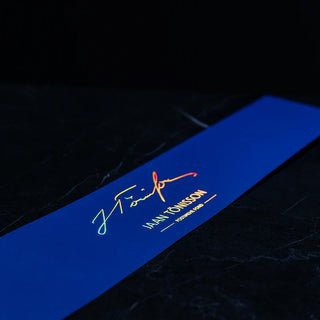 Deep blue cardstock featuring a signature in vibrant, rainbow holographic foil printing.