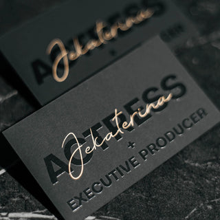 Luxury raised spot UV business cards for an executive producer featuring glossy black text on matte black cardstock.