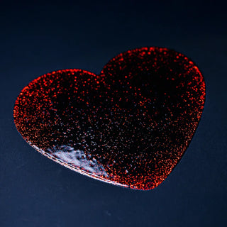 Close-up of a red heart shape featuring spot UV and foil printing with a textured, glittery finish on a dark background.