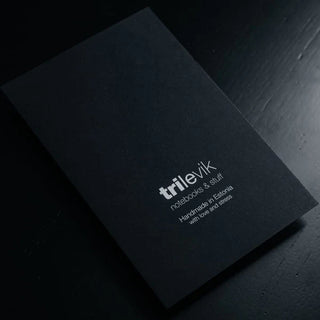 Elegantne must visiitkaart või brändimaterjal hõbedase või valge tekstiga. Kaardil on kujutatud brändi nimi "trilevik" ning kirjeldus "notebooks & stuff". Lisatekst viitab, et tooted on käsitsi valmistatud Eestis, armastuse ja tähelepanuga ("Handmade in Estonia with love and attention"). Minimalistlik ja kaasaegne disain, mis peegeldab tõenäoliselt käsitöömärkmeikute või paberitoodete brändi identiteeti. Must taust ja hele tekst loovad premium-mulje. | Trükikoda Brandcafe